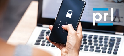 hand holding a cell phone with a security lock on it, Laptop in the background with PRL logo in upper right corner