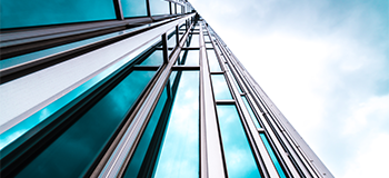 Glass Building corner against sky and white clouds